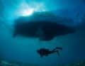 Misterioso e magico allo stesso tempo: un subacqueo galleggia lentamente sotto una barca a vela.