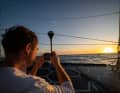 "Guyot"-Skipper Benjamin Dutreux macht ein Foto vom Sonnenuntergang. Da ahnt er noch nichts von dem Problem, das sein Team später zur Aufgabe der dritten Etappe zwingt