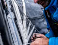 Charlie Enright pulls on the mooring line before the mainsail of "Mālama" can be fully hoisted again