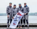 The winning team from the North German Regatta Club with the club flag.