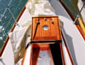 Details such as the fore hatch with porthole and hinged stands reveal the yacht's noble origins