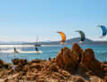 Sören, Jan e Philipp volano in formazione attraverso la baia nella luce della sera. Lo skipper professionista del cat ha esperienza di kitesurf e sceglie il prossimo spot in base alle previsioni del vento e alle preferenze dell'equipaggio. Tiene d'occhio gli ospiti che praticano il kite e, se necessario, può venire in soccorso con la costola.