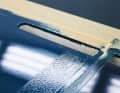 Unclean: residue from an adhesive strip causes the paint to bead up. Clean the substrate with thinner and silicone remover