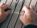 2. Mit der Klinge aus einem Cuttermesser wird die überstehende Dichtmasse bündig auf die Höhe der Teakstäbe geschnitten