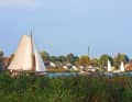 A flat-bottomed ship sails off the town of Heeg