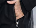 Die lange Jacke ist mit seitlichen Taschen inklusive einer Drainage versehen
