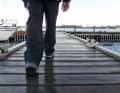 The protagonist walks across the footbridge, only his feet are visible