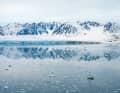L'Aluyacht "Qilak" de 66 pieds dans le champ de glace devant les montagnes enneigées et l'un des glaciers de la côte ouest du Svalbard
