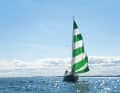 La voile d'avant s'affale. Le génois à rayures vertes et blanches est devenu une marque de fabrique