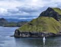 The catamaran looks tiny against the towering islands.