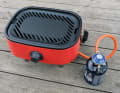 Tragbarer Grill mit praktischem Schneidebrettchen.