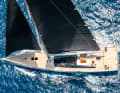 Strong colour contrasts: red crew and flag accents contrast with black sails over a black superstructure with a white hull