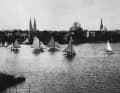 Les navigateurs du Lübecker Yacht-Club avec leurs bateaux sur la Wakenitz, avec les clochers de Lübeck en arrière-plan.