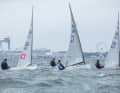 Die früheren olympischen Finn-Jollen nach dem Rennstart vor der Warnemünder Kulisse.