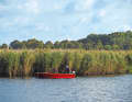 Two anglers lie with their boat in front of the reed belt
