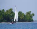 „Holly Golightly“ mit Dingi im Schlepp bei der Durchquerung der Lagune eines Atolls.