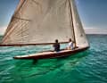 L'immense grand-voile à gaffes avec sa bôme dépassant largement de la poupe marque la silhouette de l'antique voilier de course.