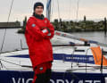 Der Wettbewerbssieger vor dem Boot, das ihn im Mini-Transat 2027 über den Atlantik tragen soll.