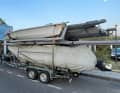 The fully loaded trailer of the Finnish national sailing team: above two 49er FX dinghies from Ovington and MacKay, three masts and several sails, below a VSR 5.8R rib used as a coaching boat with a 70 hp Yamaha outboard motor and several boxes with high-quality sailing equipment