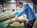A boat builder places the flax fabric for a component in the mould and positions it using a laser. Around ten people work in production, and Greenboats also trains them