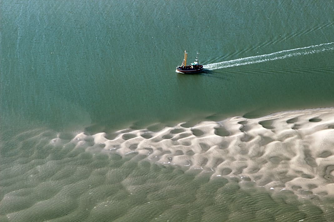 Ein einsamer Kutter passiert eine Sandbank bei Langeoog