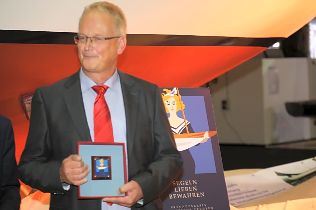 Eigner Jens Burmester freut sich sichtlich über die von Hinnerk Bodendieck gestaltete Auszeichnung, die in der Kajüte seiner "Astra" einen Ehrenplatz bekommen soll