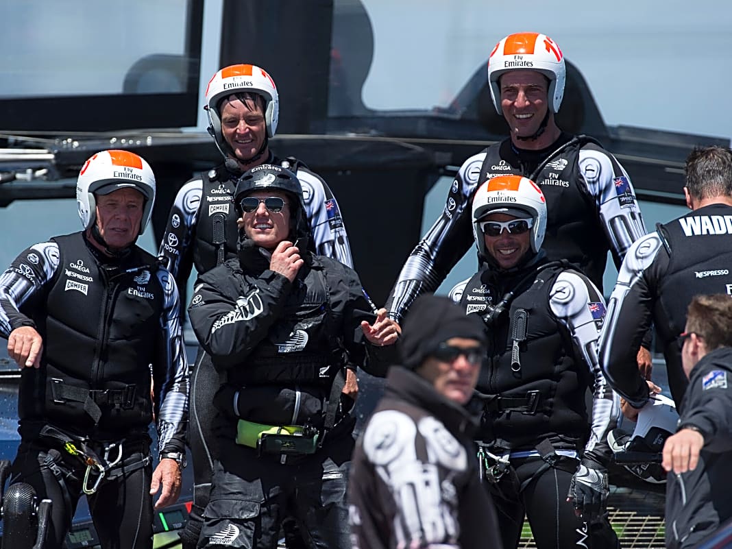 Tom Cruise (schwarzer Helm) neben Grant Dalton und zwischen den Seglern von Team New Zealand