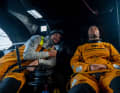 Crew-Kamerad Phillip Kasüske zeigt lächelnd auf seinen Skipper, der sich kurz ausruht
