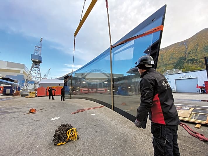   Diffizile Montage: Im Kran hängt die 11,20 Meter lange und gebogene Frontscheibe für die Observation-Lounge von „REV Ocean” auf Deck neun. Sie wiegt stattliche 4,5 Tonnen.  