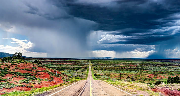   Eine dieser typisch schnurgeraden Straßen zieht sich durch die Ebene von New Mexico. Darüber wölbt sich ein imposanter Gewitterhimmel.  