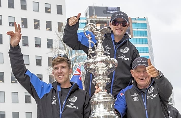   Dieses neuseeländische Triumphbild mit Grant Dalton, Skipper Glenn Ashby und Steuermann Peter Burling (v.r.) entstand nach dem Bermuda-Sieg 2017. Man könnte es jetzt wieder verwenden, denn alle Schlüsselmitglieder im Emirates Team New Zealand sind geblieben und haben erneut gemeinsam gewonnen…