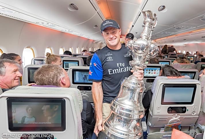   Vorbereitung im Flieger: Skipper Glenn Ashby trägt den America's Cup durch die Reihen
