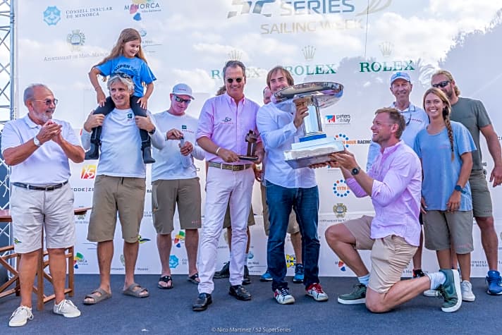   Die glücklichen Sieger von Menorca: Harm Müller-Spreer in der Mitte im rosa Hemd mit Teilen seiner Crew und einem kleinen Fan sowie dem begehrten Royal Cup