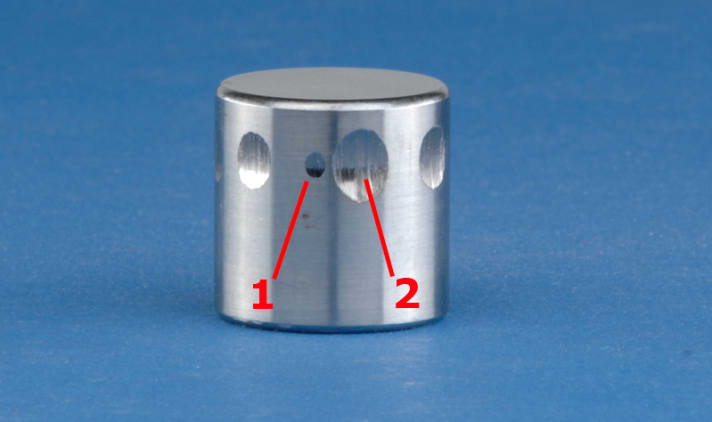 Clairement : un cylindre d'essai du test Brugger montre les différentes capacités de lubrification : un très bon lubrifiant se reconnaît à sa petite surface d'usure (1), un moins bon à sa grande surface d'usure (2).