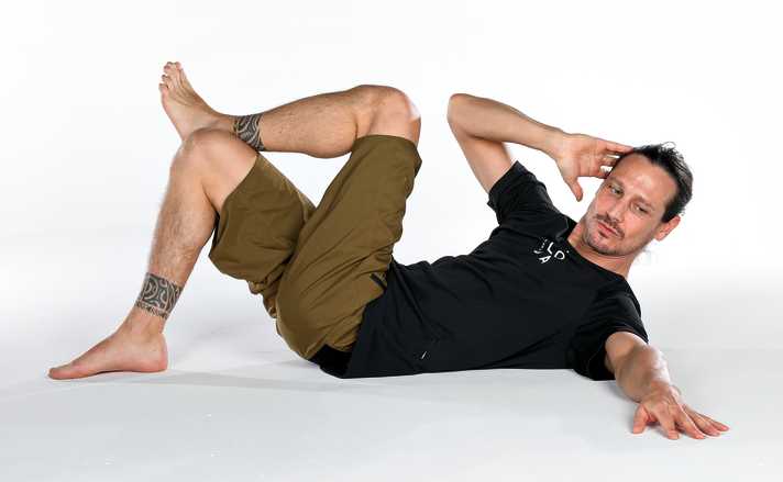 The gaze guides the movement. The elbow touches the knee.