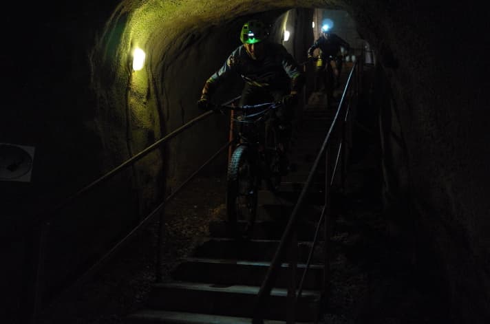   Vom Eingangstunnel aus führt eine steile Eisentreppe ins Stollensystem. Für die Downhill-Rennfahrer Lucas und Nina ein willkommener Aufwärm-Kick.