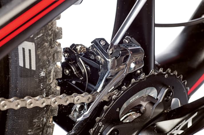 Zum Einstellen der unteren Begrenzung muss die L-Schraube am Umwerfer soweit gedreht werden, dass die Kette das innere Leitblech gerade nicht berührt.