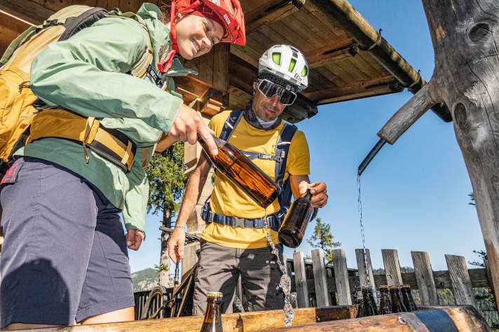 Im Herbst gibt es auf der Blaubergalm leider keine Blaubeeren mehr, aber Leoni und Appi dürfen sich ein Bier aus dem kalten Brunnen vor der Hütte fischen.