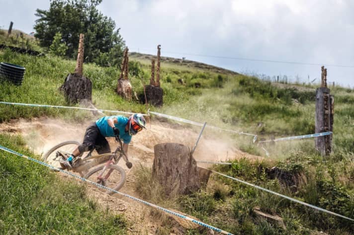   Speedster: Staubig, schnell, rutschig – der obere Teil der UCI Strecke fordert die meisten Sturzopfer im Worldcup. Im Hintergrund: Holzskulpturen mit den Namen der Gewinner. 