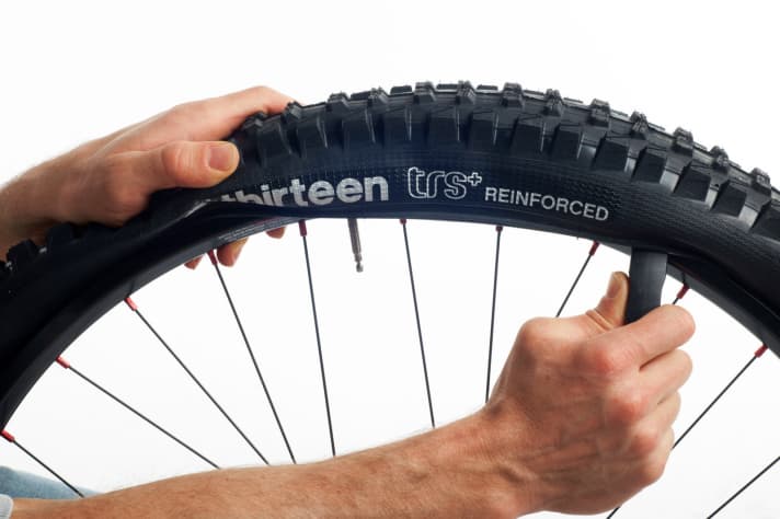 Um den Fahrradschlauch zu wechseln, reicht es den Reifen nur auf einer Seite aus der Felge zu hebeln. Beginnen Sie am Ventil und arbeiten Sie sich entweder durch Schieben (Bild) oder Ziehen weiter vor, bis sich der Reifenwulst aus der Felge löst.