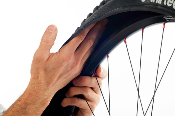 Entfernen Sie den defekten Fahrradschlauch und suchen Sie den Reifen innen (durch Tasten mit der Hand) und außen auf Fremdkörper ab. Dornen, Steinchen oder ähnliches müssen entfernt werden, bevor Sie den neuen Schlauch einlegen.