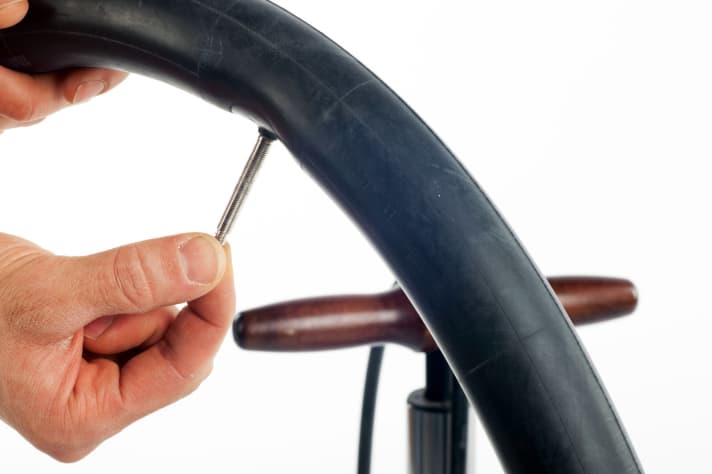 Pumpen Sie den neuen Fahrradschlauch leicht auf, damit er sich nicht verknotet oder verdreht, und drehen Sie das Ventil wieder zu. Er sollte nur so weit aufgepumpt werden, dass er keine Knicke mehr aufweist, sich aber noch gut einlegen lässt.