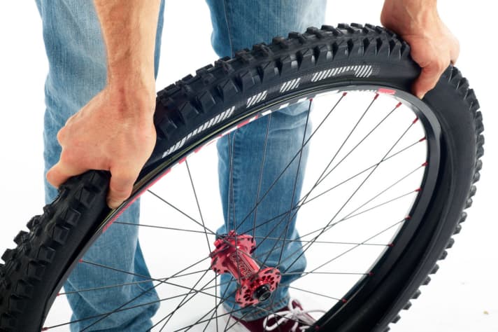  Now comes the all-important step in fitting the tyre: Start opposite the valve and press the tyre bead deep into the rim well. Continue to work your way towards the valve on both sides of the tyre.