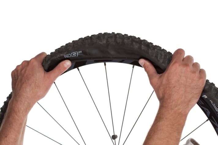 Fitting the tyre If you had removed the tyre completely, first pull it into the rim all the way round with one side. Now insert the slightly inflated inner tube. Starting at the valve, use your thumbs to press the second side of the tyre into the rim.
