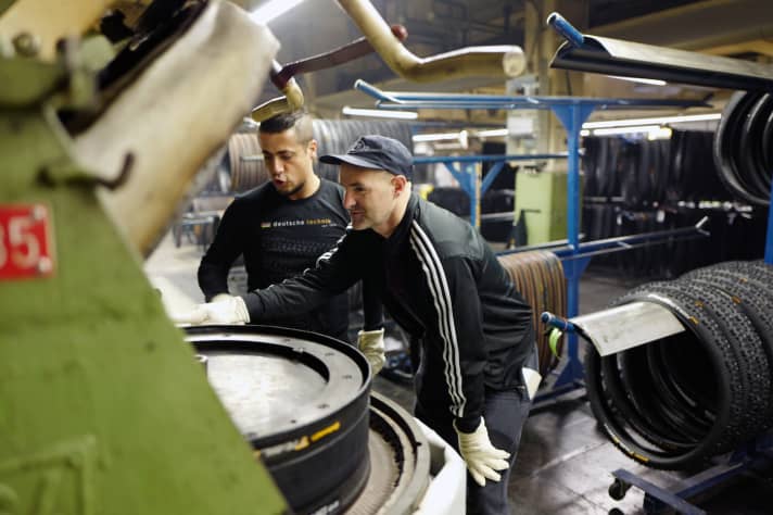   Hossa! Hier ist es ja heiß wie in einer äquatornahen Klimazone! Vulkanisation, nennt sich die dampfende, zischende Abteilung, in der die Rohlinge zu fahrfertigen Reifen gebacken werden. 172 Grad, 15 bar Druck, 280 Sekunden. Rohling rein, Knopf drücken, warten, Reifen rausnehmen, fertig. Conti-Spezialist Alexander Abdo zeigt, wie es geht. Insgesamt gibt es zirka 60 dieser Heizpressen.