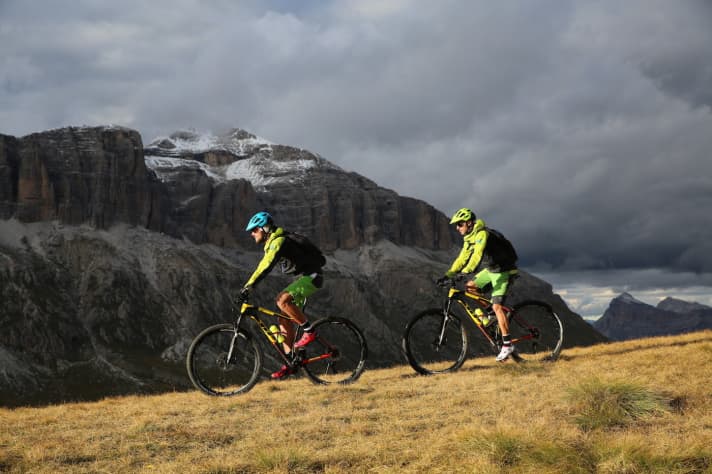   Biker vor dem Sellastock, der verschneite Gipfel hinten ist der Piz Boé.