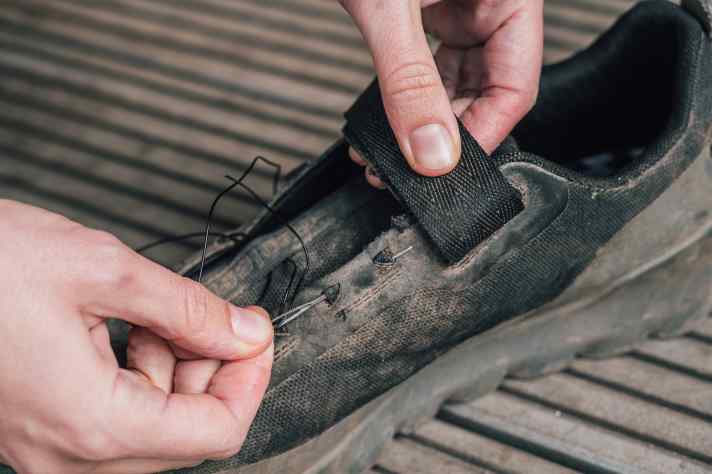 Eine Nadel hilft dabei, den Senkel durch die Stofflaschen zu fädeln