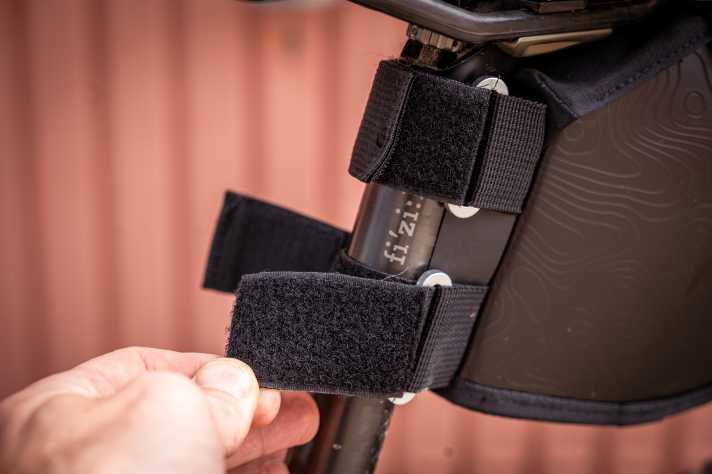 L'étui est fixé à la tige de selle par deux bandes velcro solides et tient parfaitement bien.