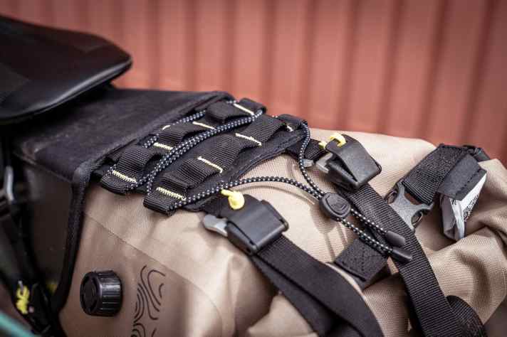 le haut de l'étui offre de la place pour les accessoires, qui peuvent être fixés par le filet élastique ou par les boucles