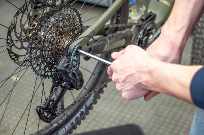 Next, loosen the main screw of the rear derailleur.